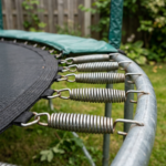 Close-up view of metal springs attached between trampoline mat and metal frame